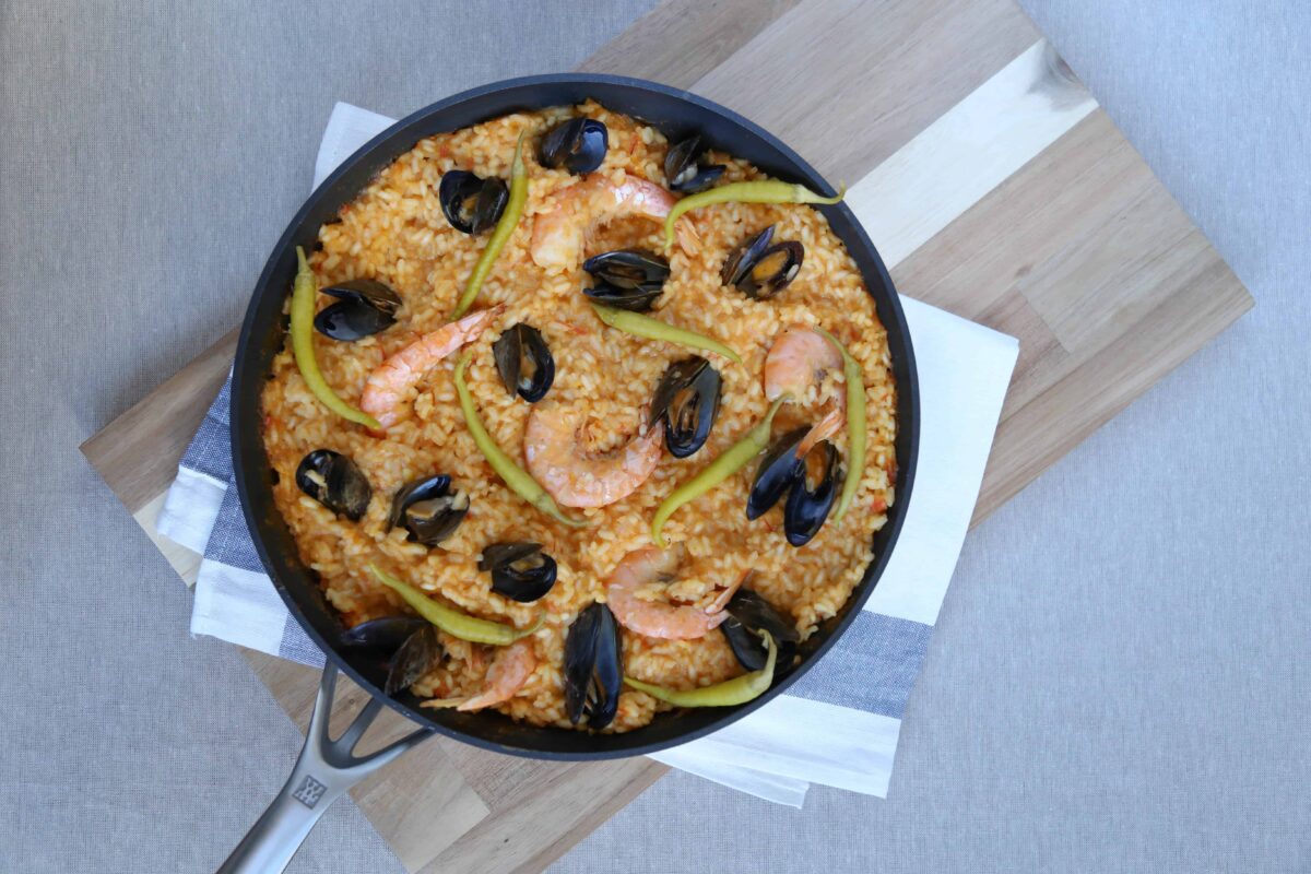 paella topped with mussels and shrimp on a towel on top of cutting board.