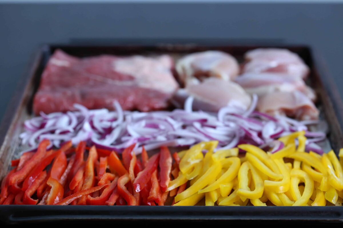 peppers, onion, and meat on a sheet pan