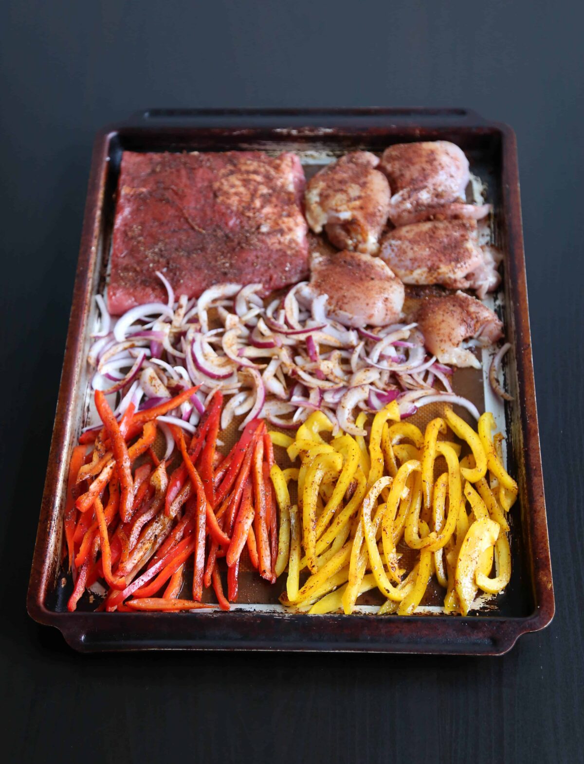 seasoned meat and vegetables on a sheet pan
