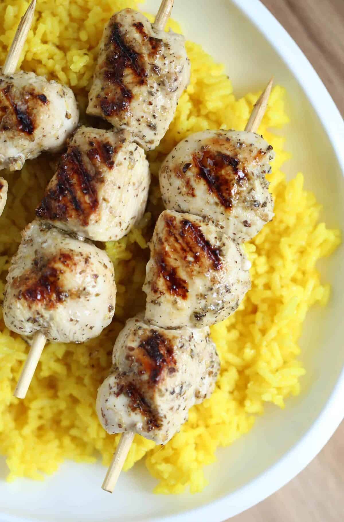 Greek Chicken Souvlaki on a bed of golden rice, on a white platter