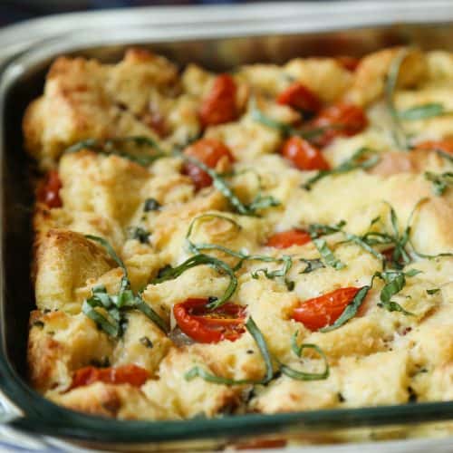 caprese bread pudding in a glass casserole dish, topped with shredded basil.