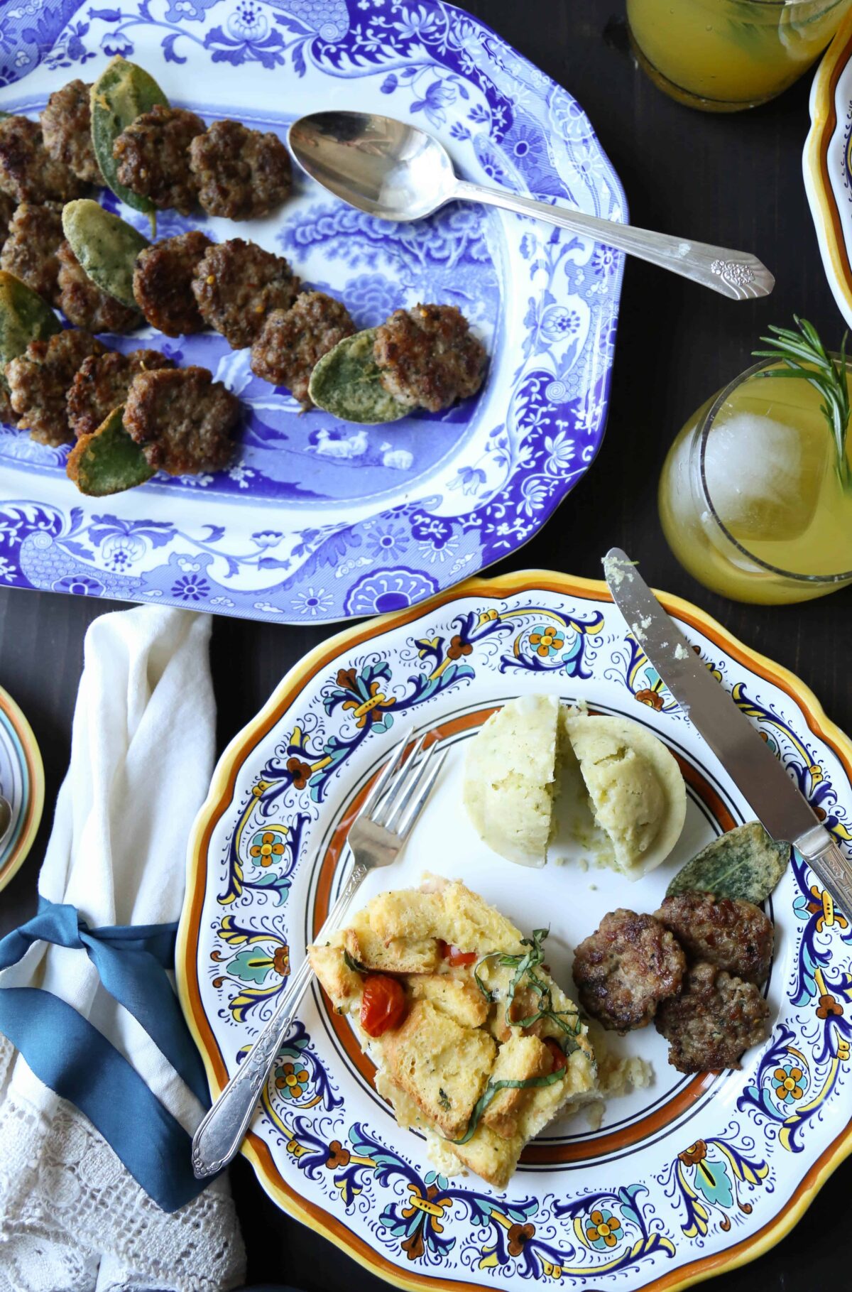 table set with colorful china with sausage patties, muffins, and an egg casserole on the plate.