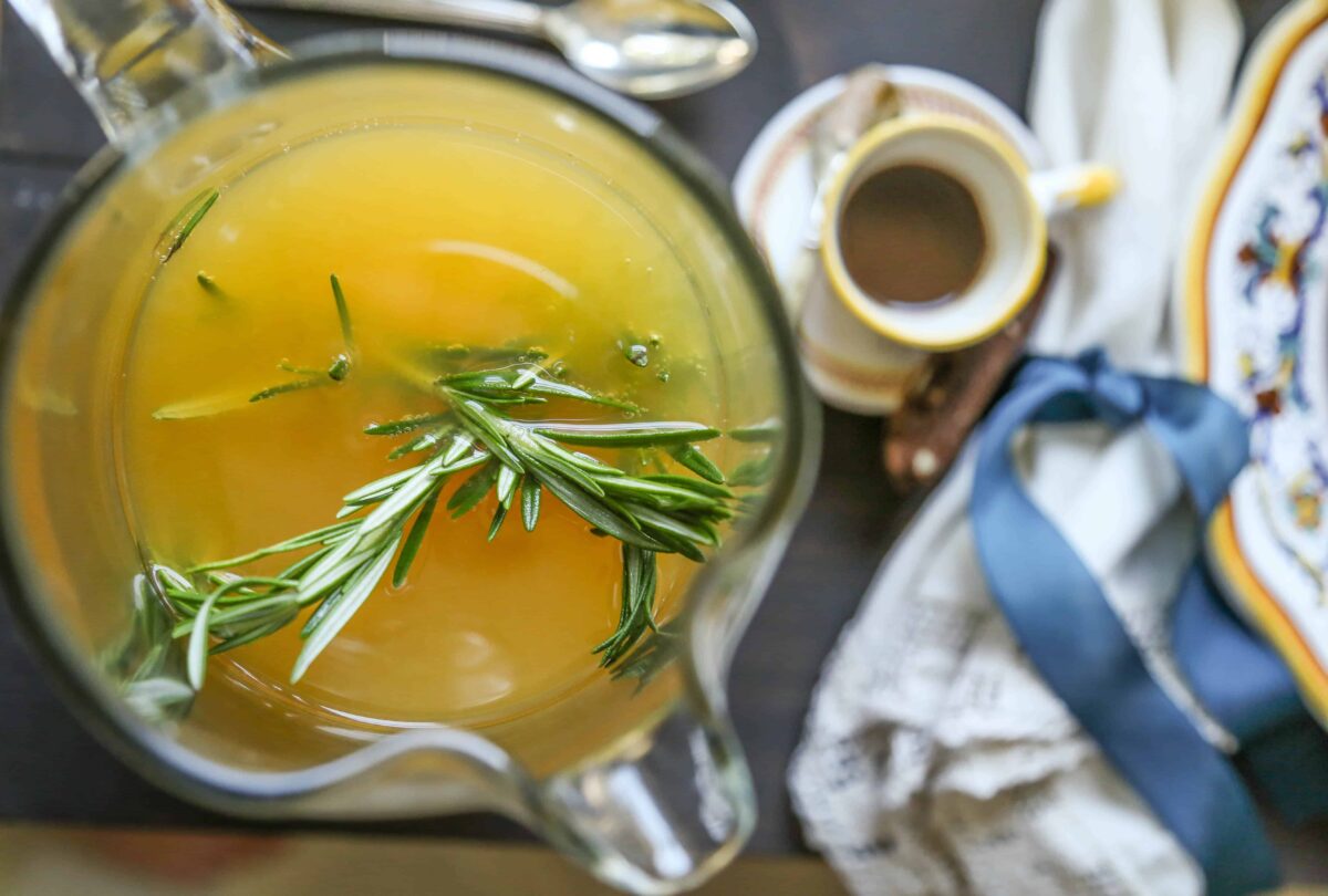 pitcher of rosemary clementine cocktail with rosemary sprigs.