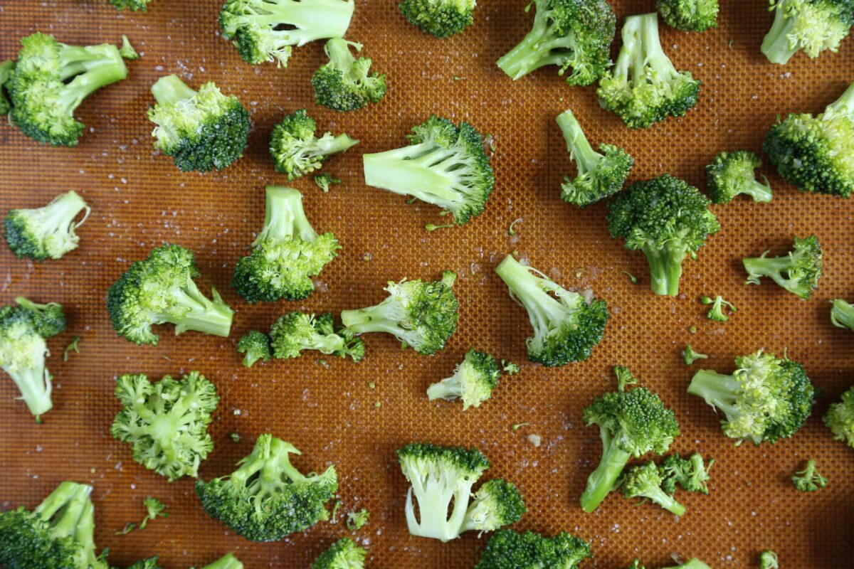 raw broccoli florets on a baking sheet.