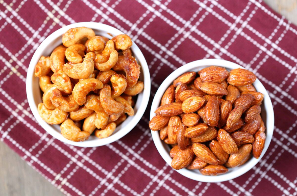 two bowls of roasted nuts sitting on a burgundy tea towel.