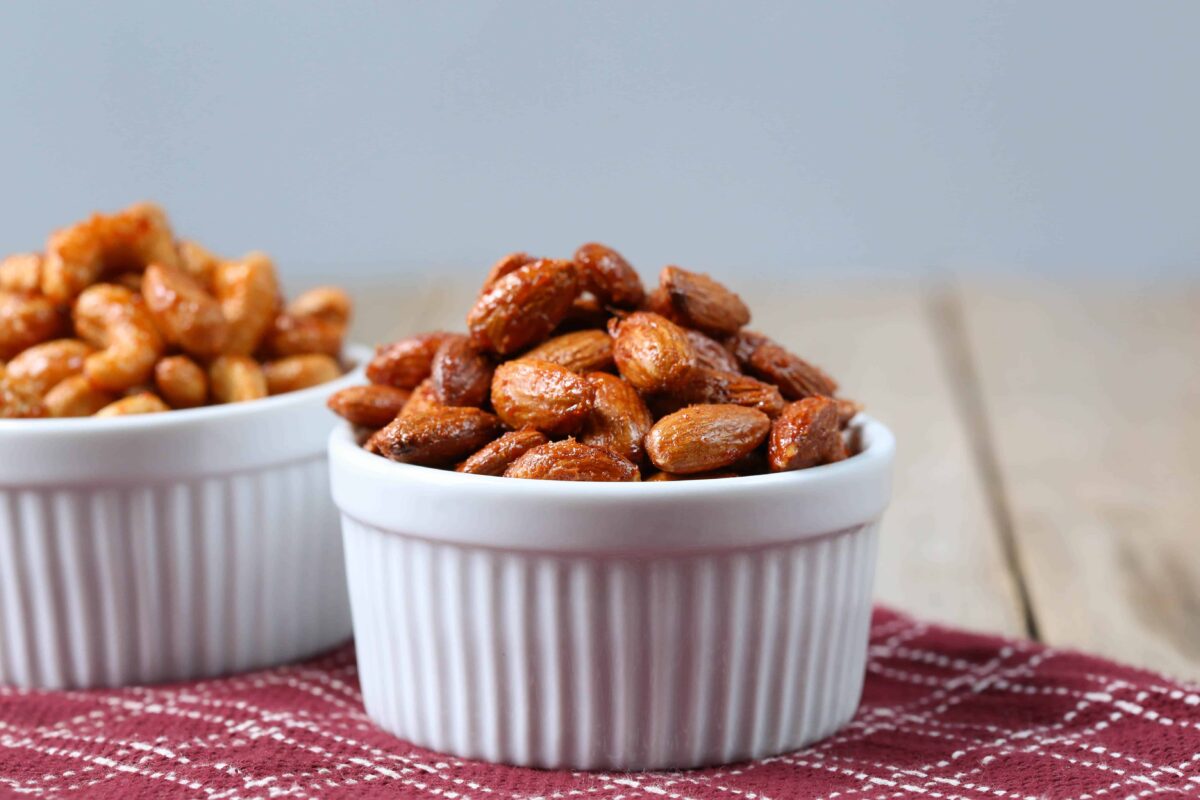 roasted almonds in a white bowl on a burgundy tea towel.