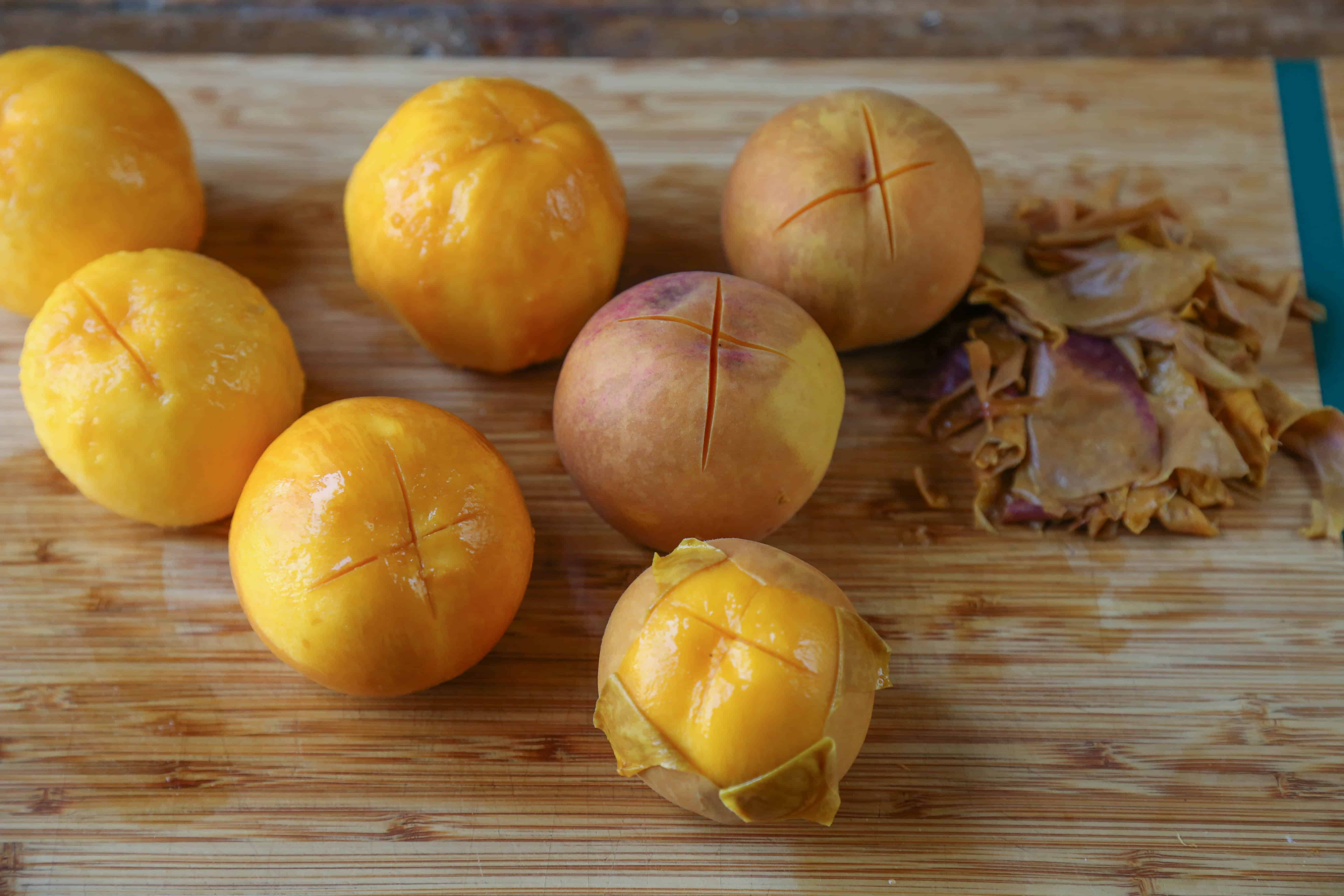 peeled peaches on a cutting board with peach skins nearby
