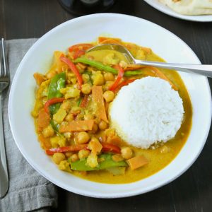 vegetarian curry and a mound of white rice in a shallow white bowl.