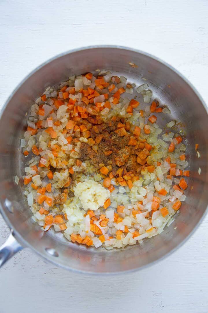 onions, carrots, and spices in a pot.