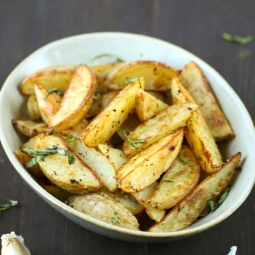 crispy garlic potato spears in a cream colored bowl.