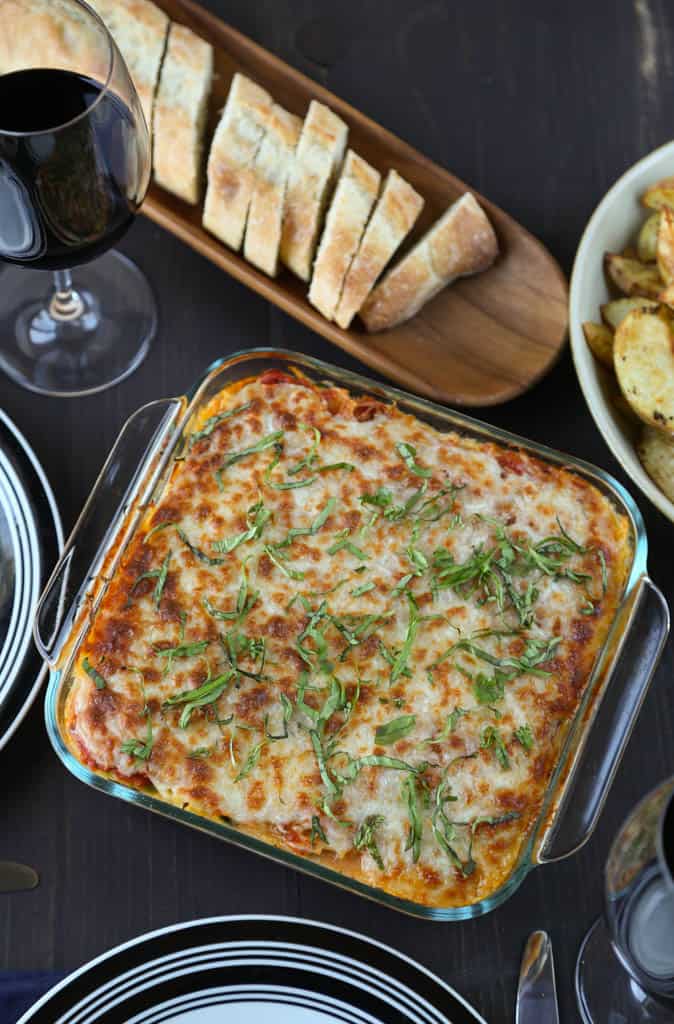 spaghetti squash lasagna on a dinner table with plates and sliced french bread.