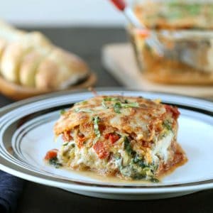 slice of lasagna on a white plate with a black rim.