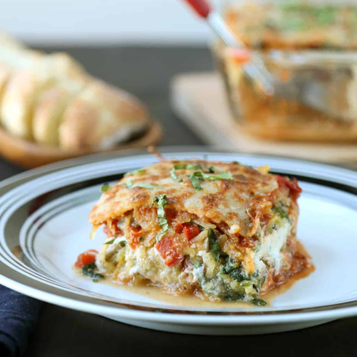 slice of lasagna on a white plate with a black rim.