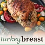 turkey breast on a platter surrounded by kumquats and pomegranates.