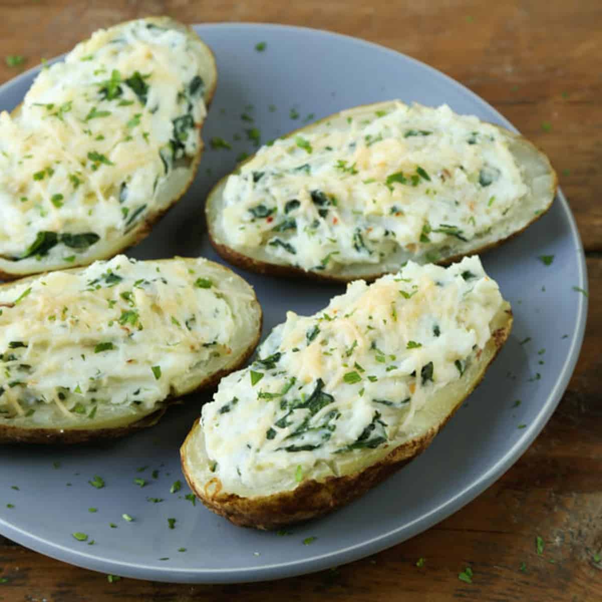 spinach artichoke stuffed potato halves on a gray plate.