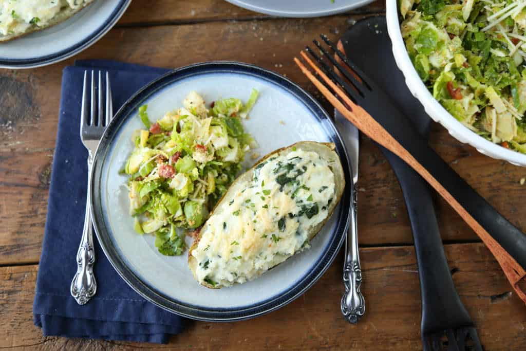 stuffed potato and brussels sprout salad on a white and blue dinner plate.