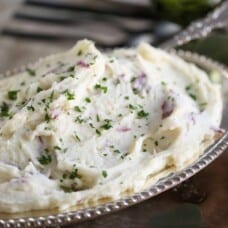 mashed potatoes with chopped parsley in a silver dish.