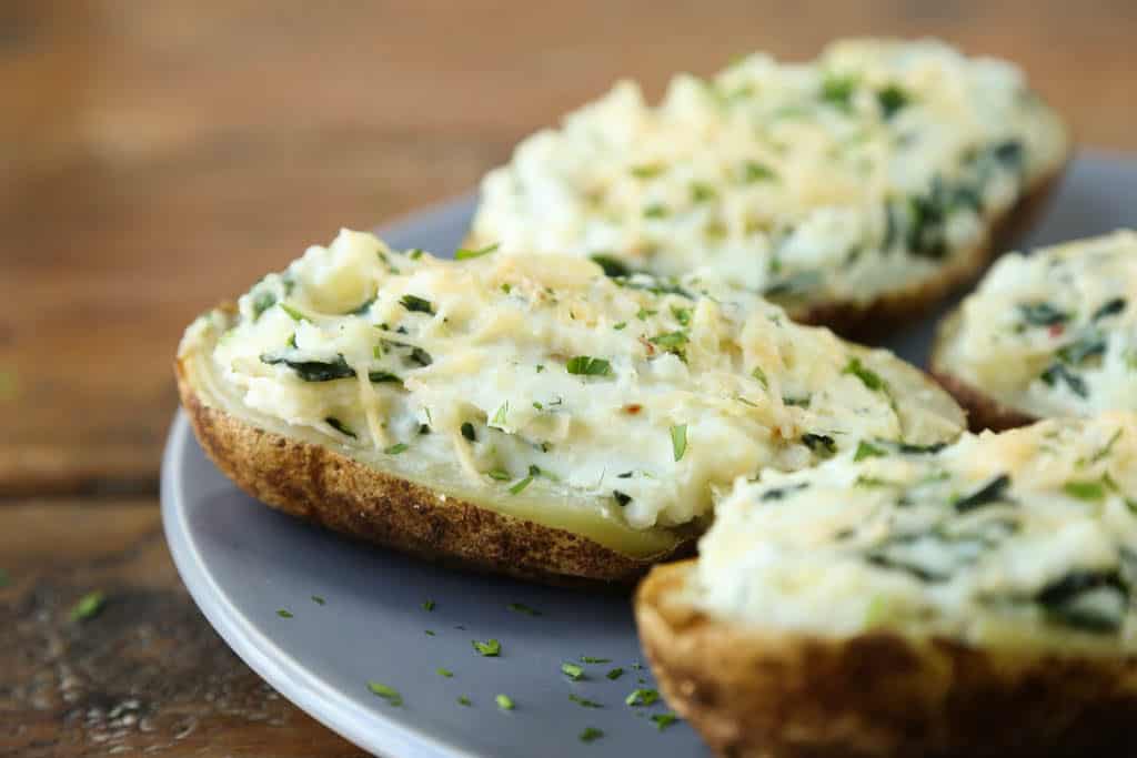 spinach artichoke stuffed potatoes on a gray plate on a wooden table.