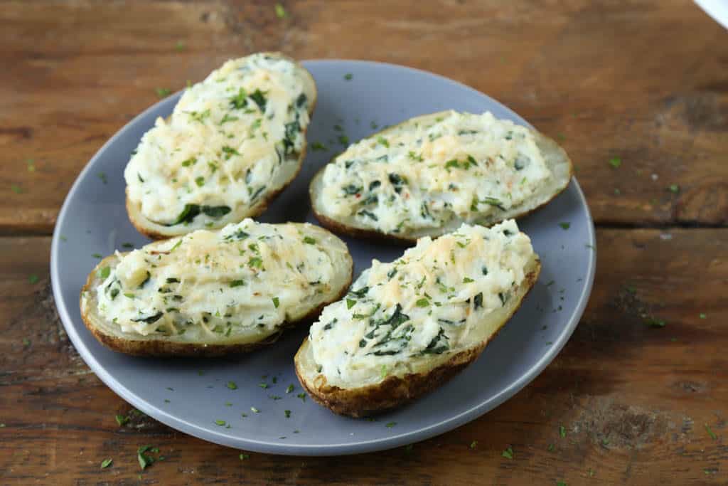 gray plate with spinach artichoke stuffed potatoes on a wooden table.