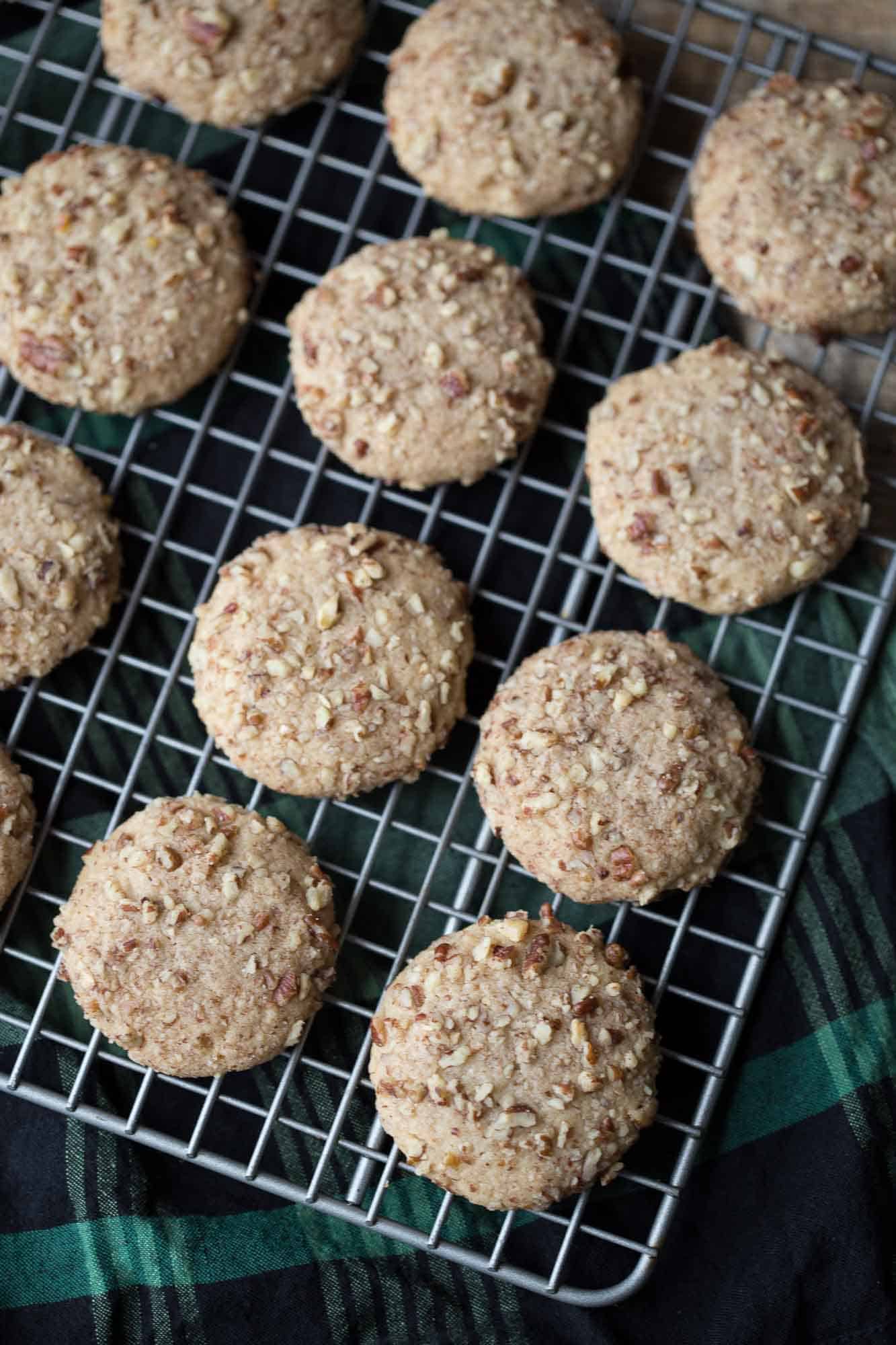 do re mi cookies on a wire rack sitting on a green and black plaid tea towel.