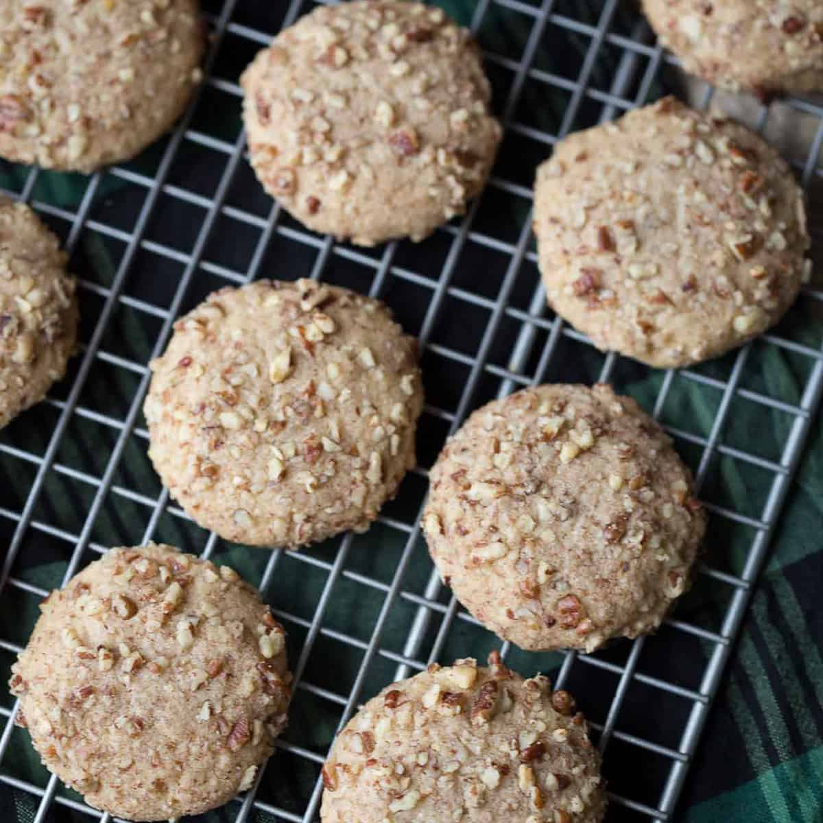 do re mi cookies on a wire cooling rack sitting on top of a green and black plaid towel.