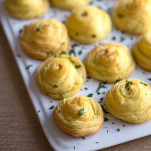 mashed potatoes piped into rounds on a white rectangular platter.