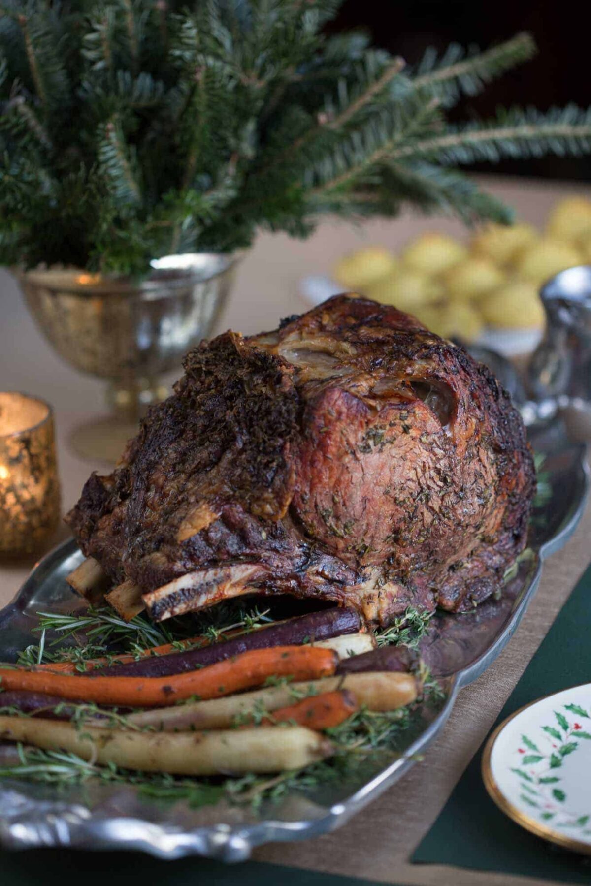 herb prime rib on a metal platter with roasted carrots.