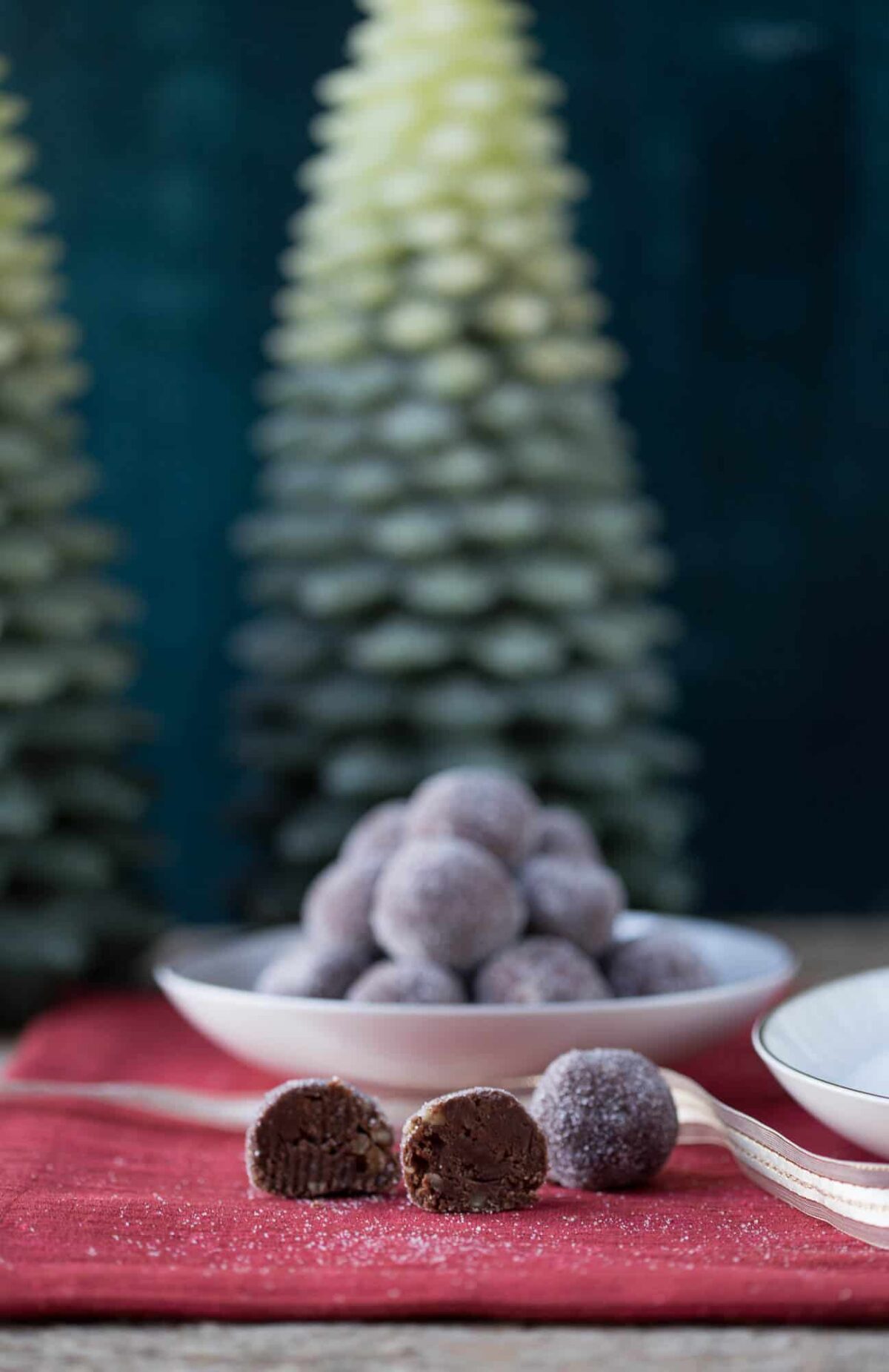 rum balls on a red placemat in front of wax christmas trees.