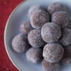 rum balls stacked in a white dish on top of a red tablecloth.