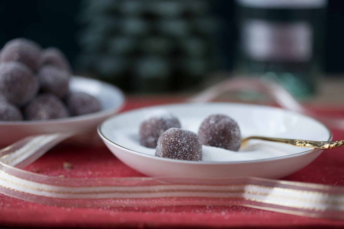 rum balls sitting in a shallow dish filled with sugar.