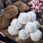 snowball cookies on a cookie tray with ginger cookies and peppermints in the background.