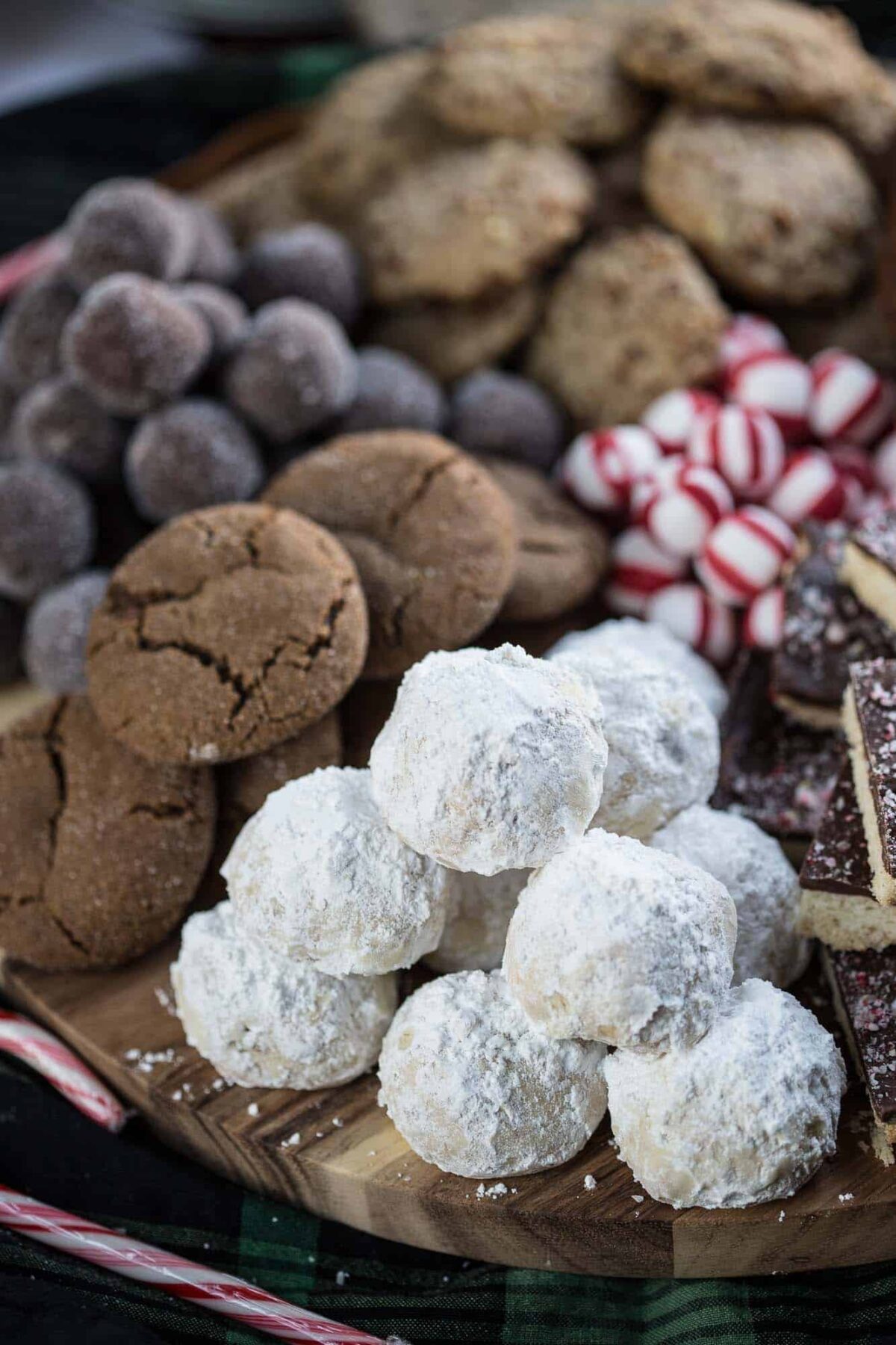 snowball cookies on a wooden platter with an assortment of christmas cookies.