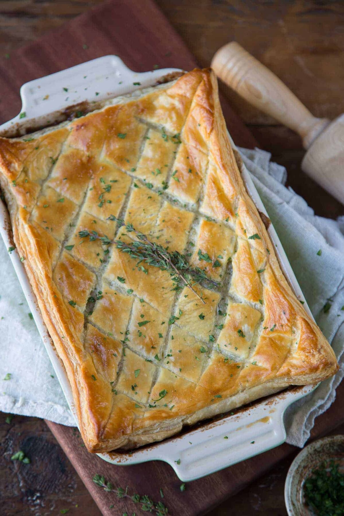 beef wellington pot pie topped with puff pastry and fresh thyme.