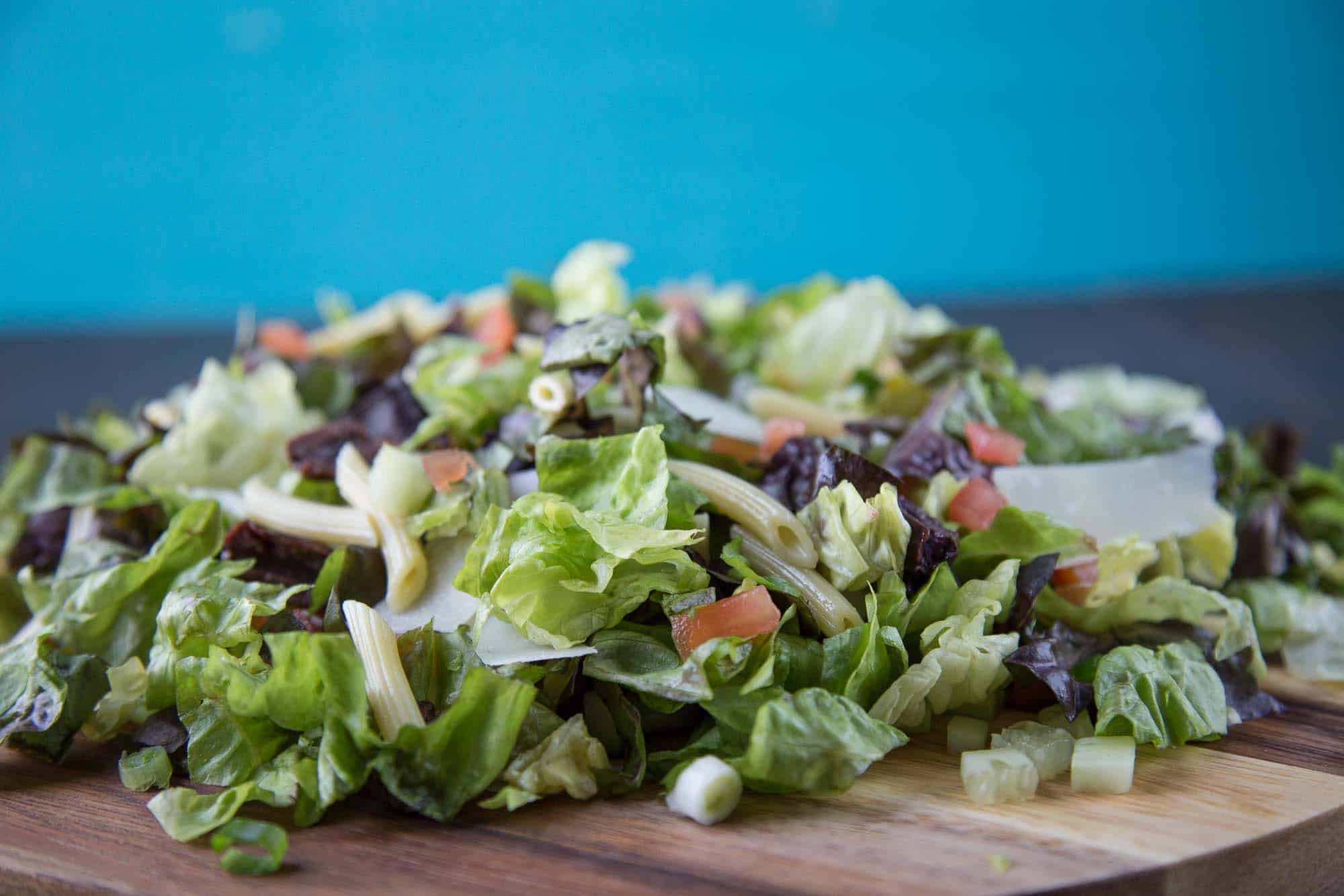 chopped salad mixed together on a round wooden platter.