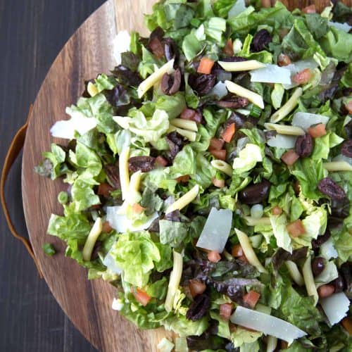 italian chopped salad on a round wooden serving platter.