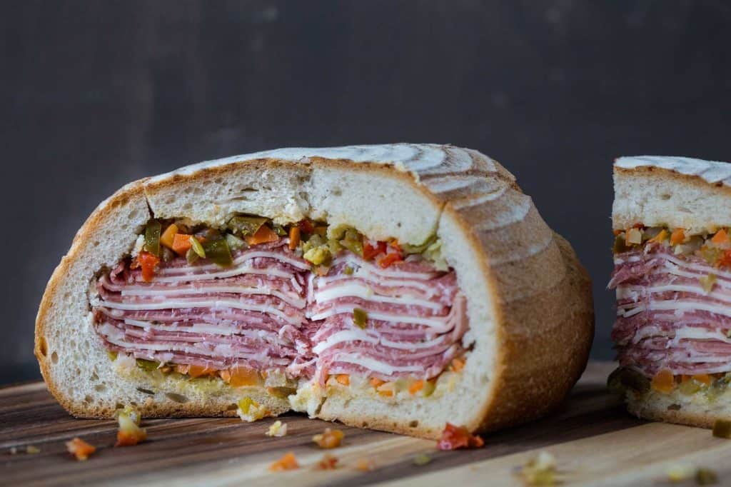 cross section of a gigantic muffaletta on a wooden board