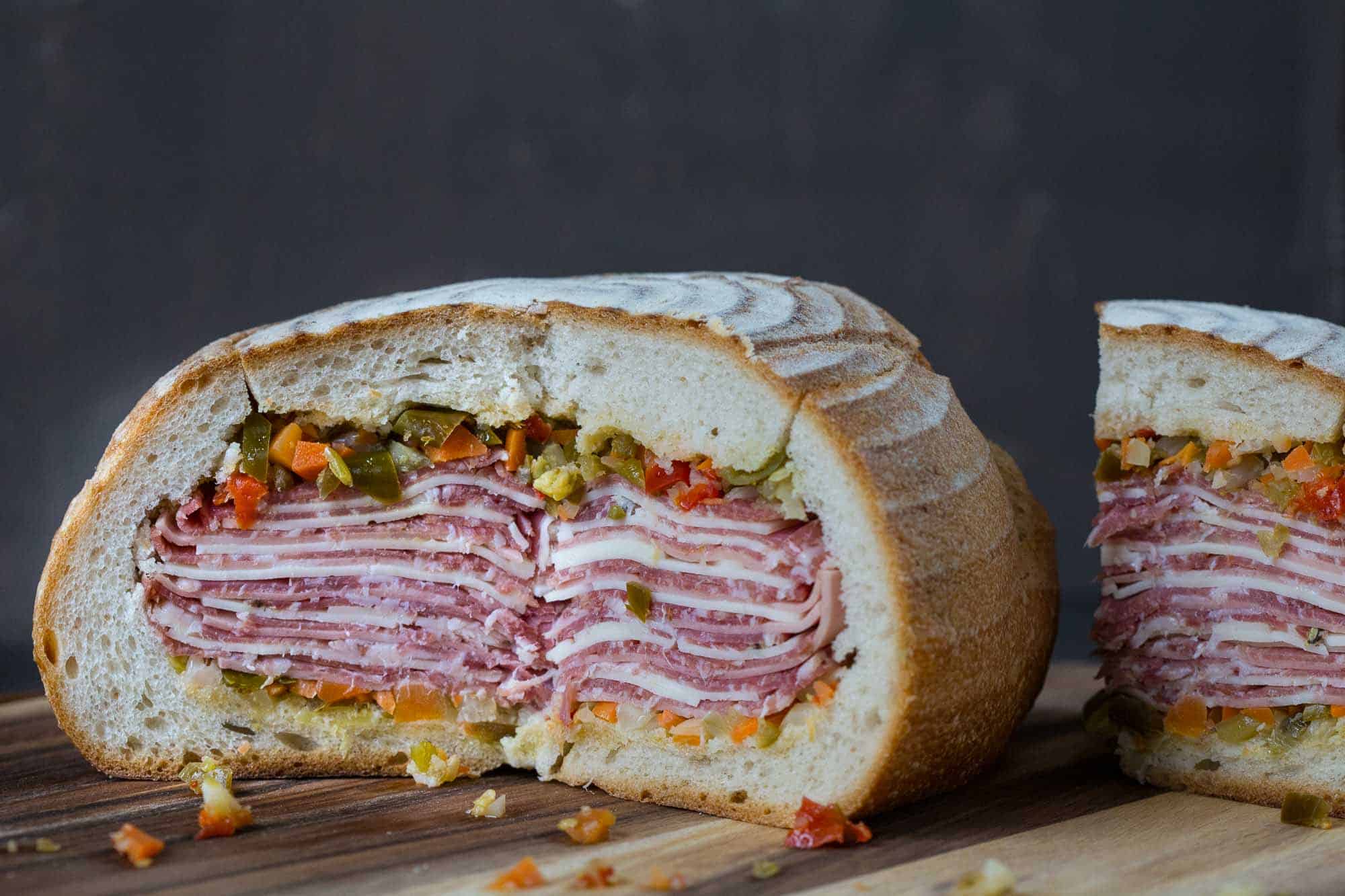 cross section of a gigantic muffaletta on a wooden board.