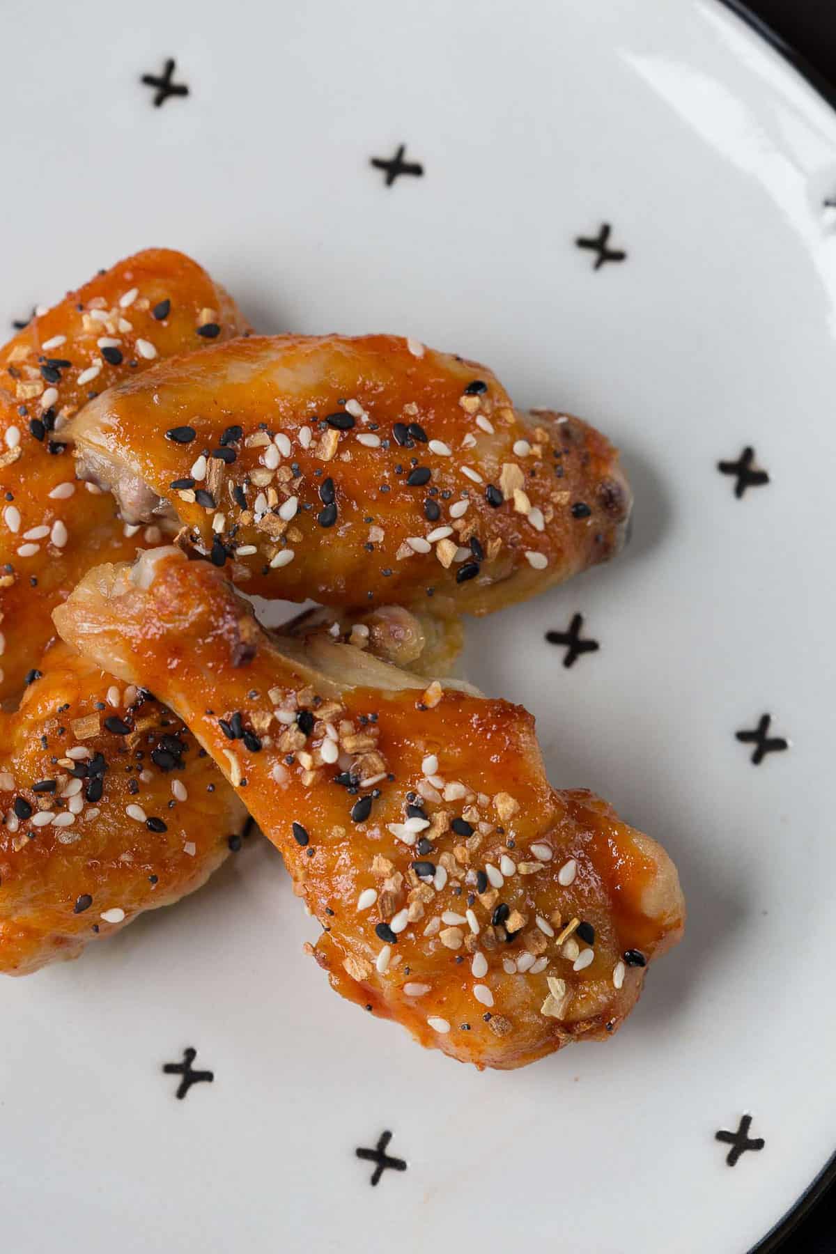 wings topped with everything bagel seasoning on a white plate with decorative X's on it.