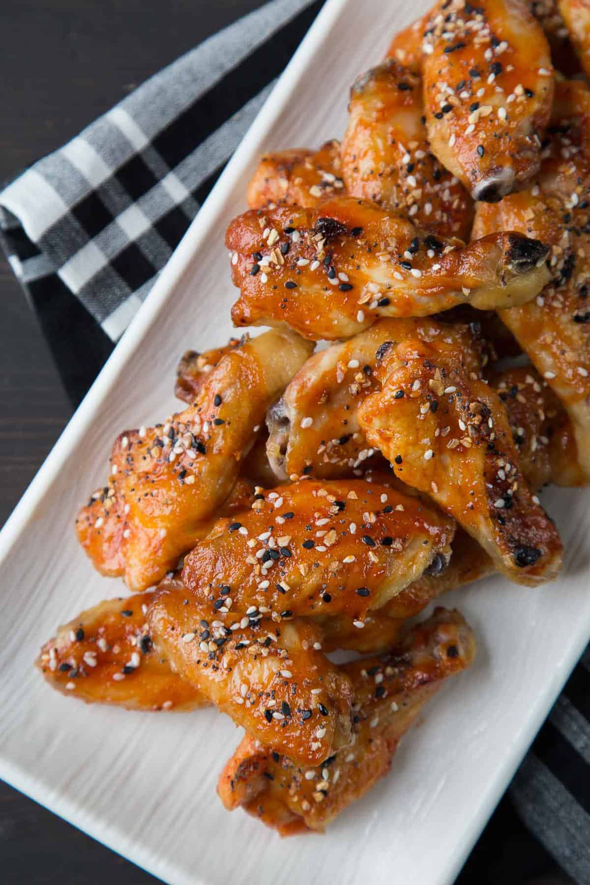 sweet and spicy wings topped with everything bagel seasoning on a white platter.