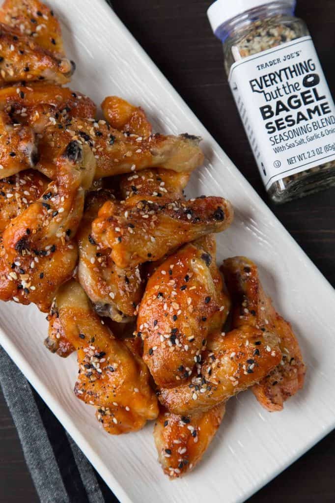 sweet and spicy wings on a white platter next to a jar of everything bagel seasoning.