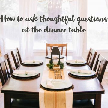 wooden table set for dinner with a table runner and a small lantern in the middle.