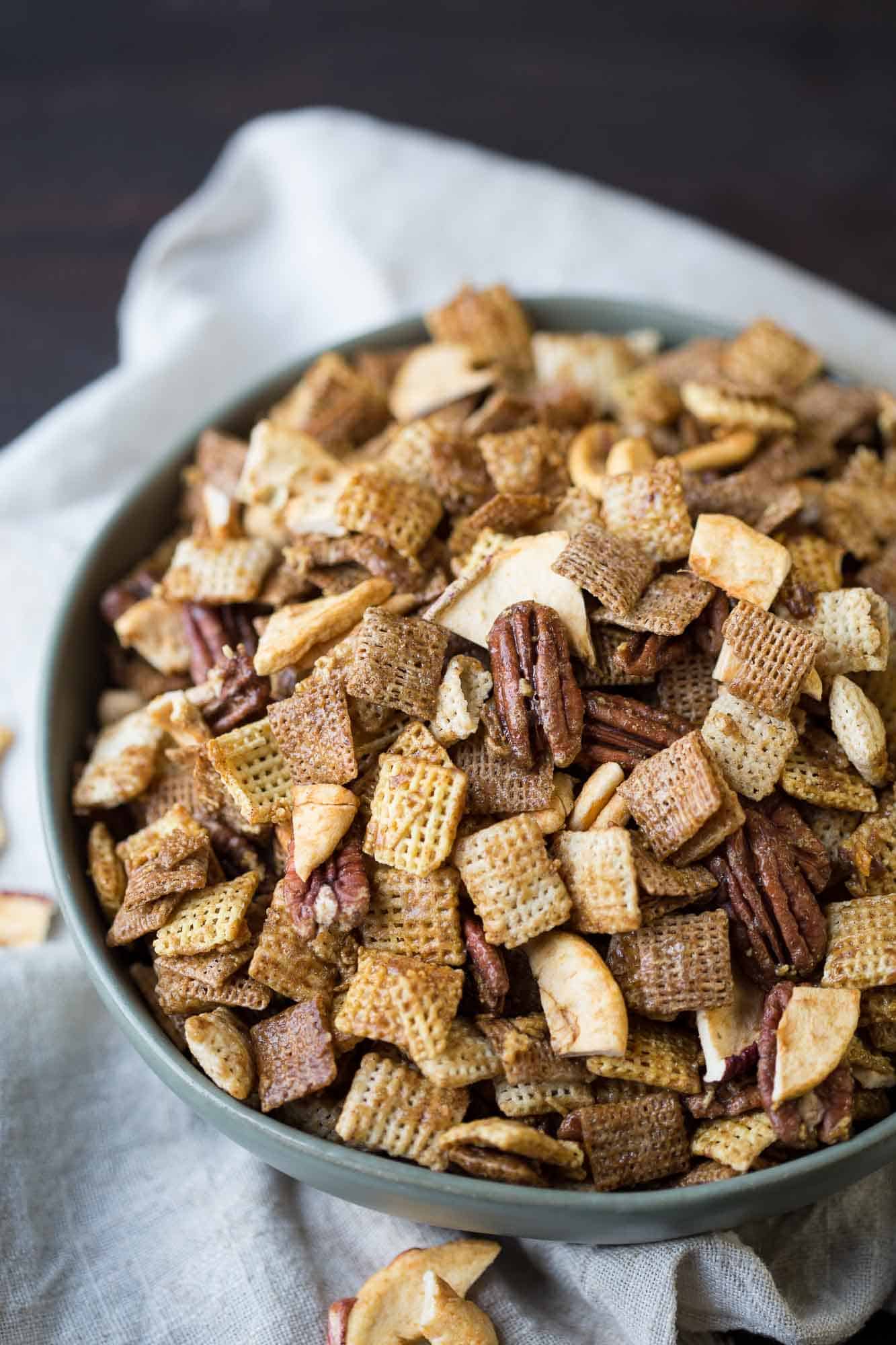 apple cinnamon chex mix in a green bowl on top of a cream tea towel