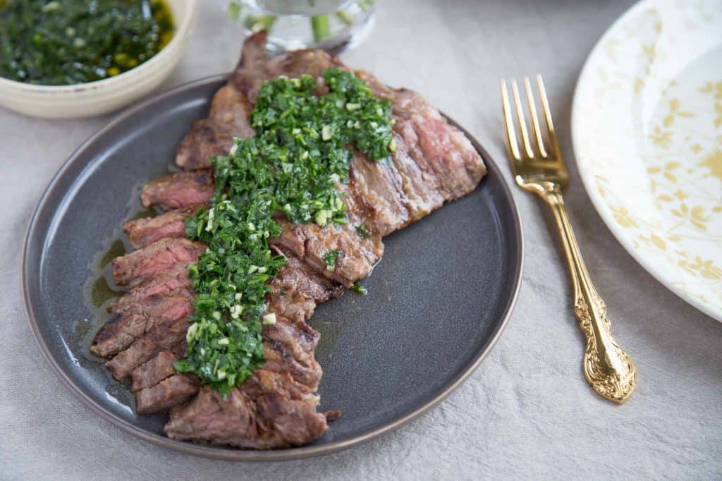 skirt steak with chimichurri on a gray plate