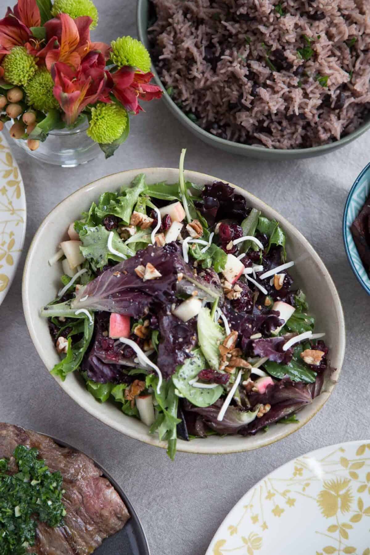 cream bowl filled with winter fruit salad on a table with rice and steak.