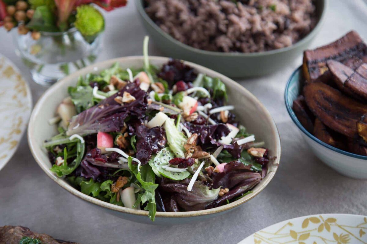 winter fruit salad in a cream bowl next to a bowl of rice and a platter of steak.