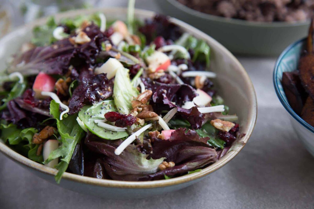 leafy green winter fruit salad in a cream bowl.