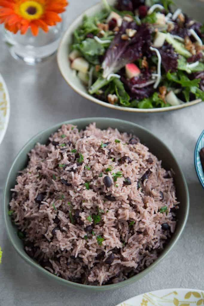 arroz moro in a green bowl on a dinner table with a salad.
