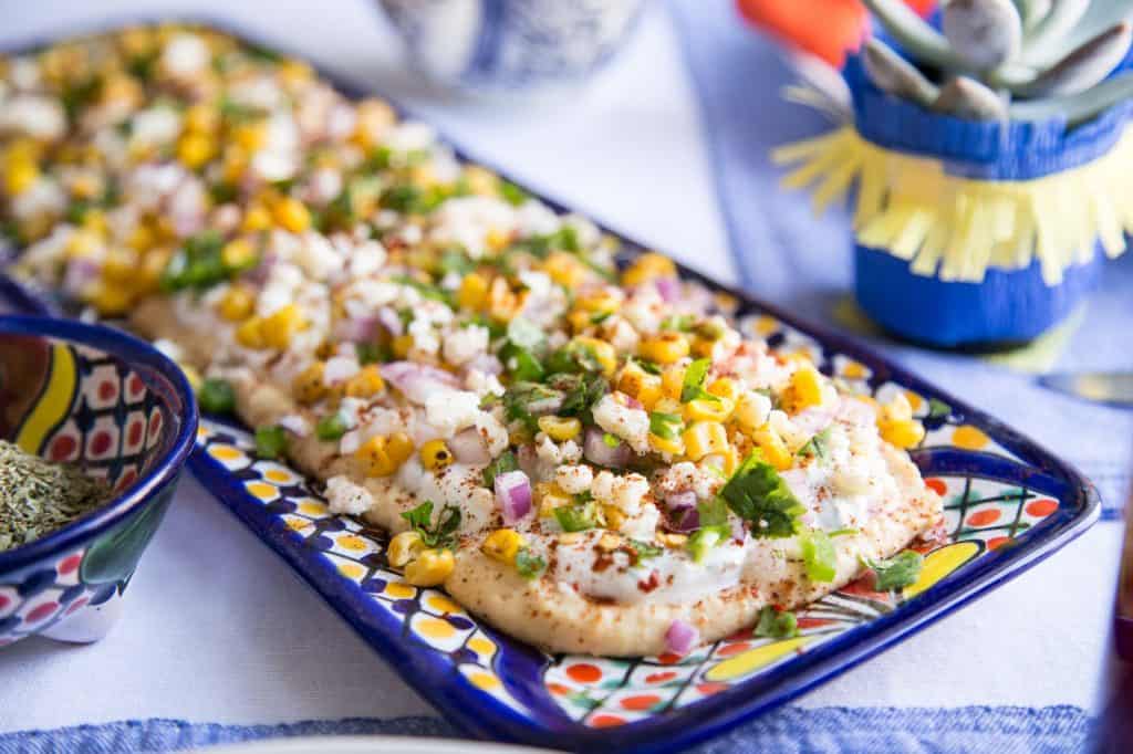 elote dip on a colorful rectangular dish.