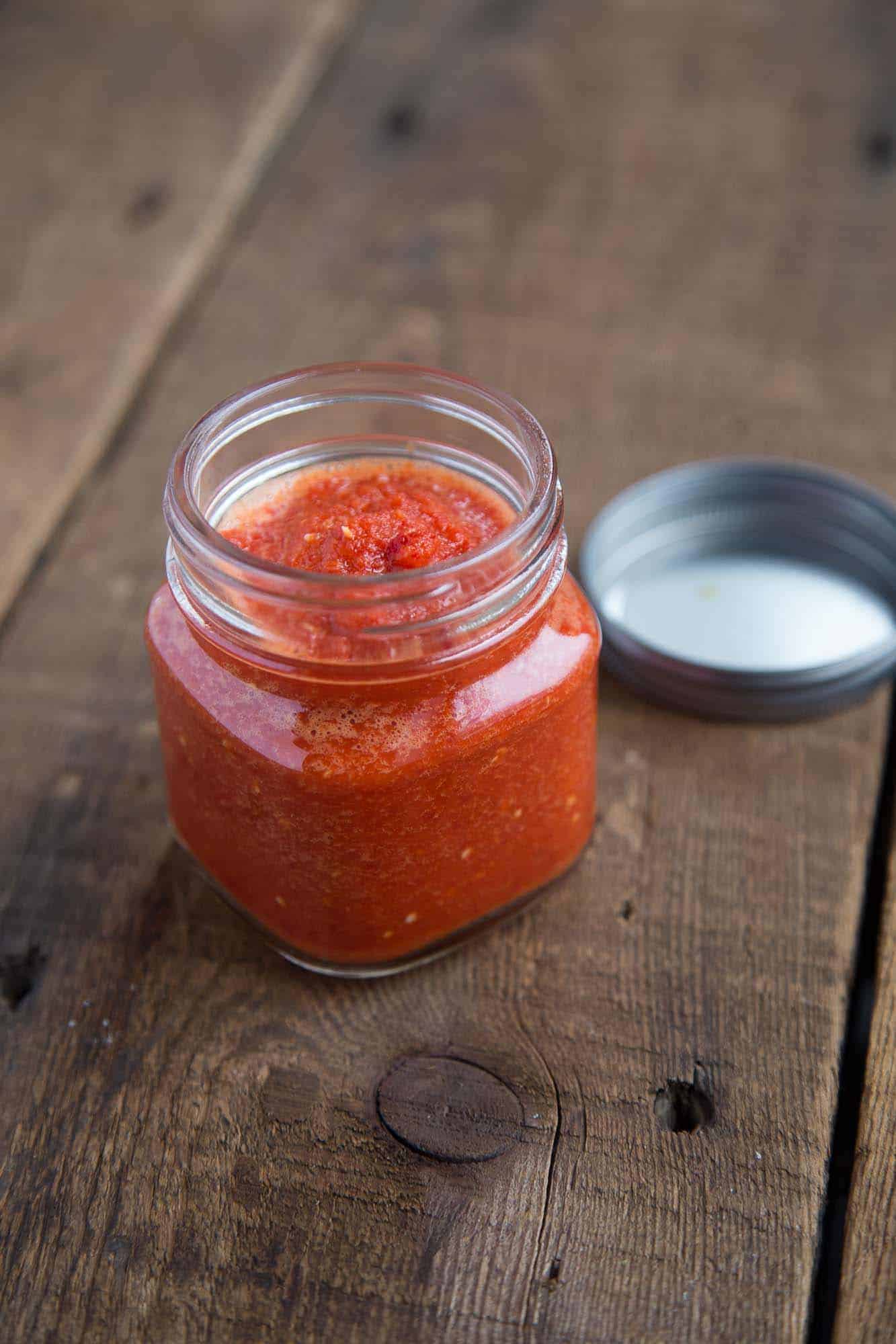 Pili Pili African Hot Sauce in a glass jar on a wooden table