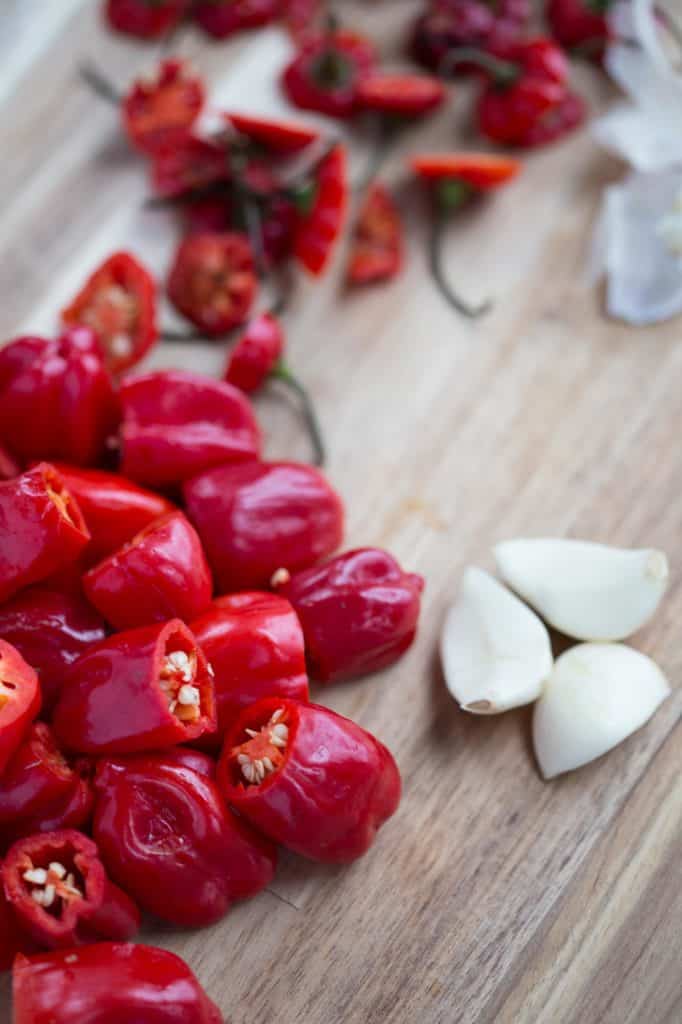 scotch bonnet peppers and garlic on a wooden cutting board